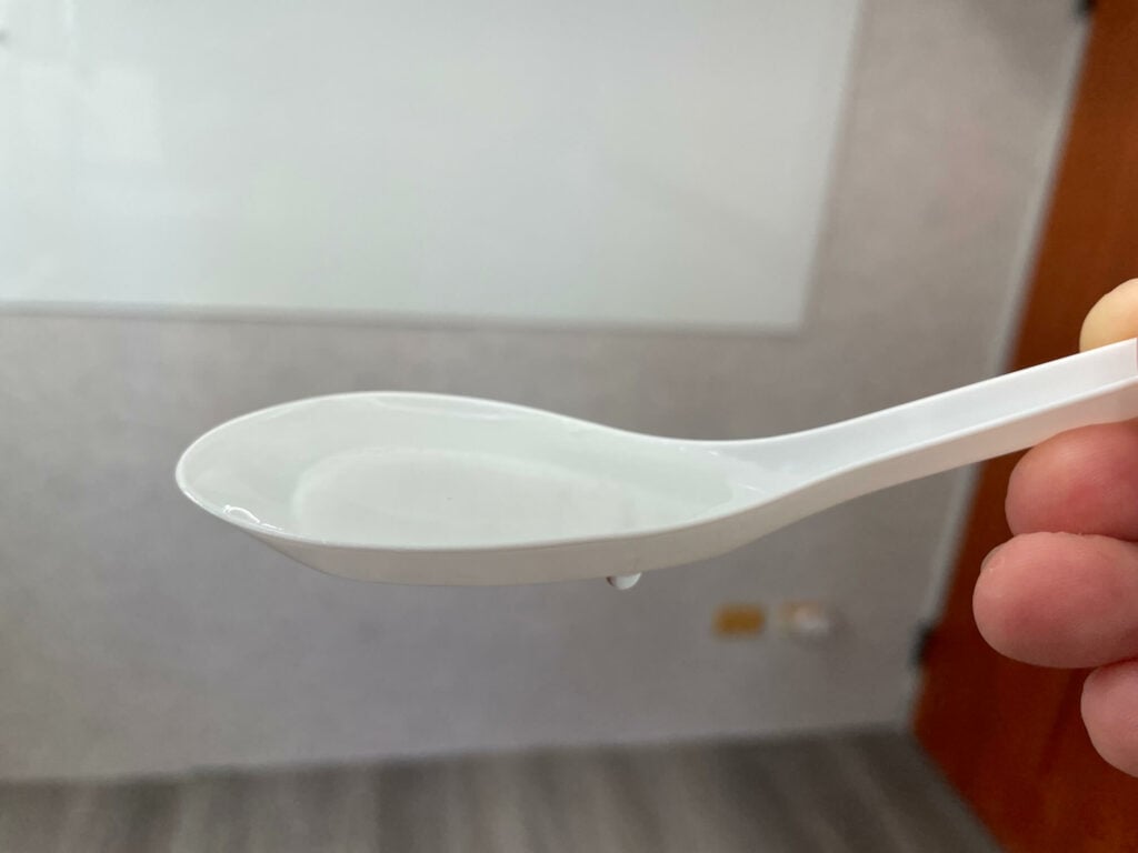 一隻白色免洗湯匙，容量大約就是 15cc。